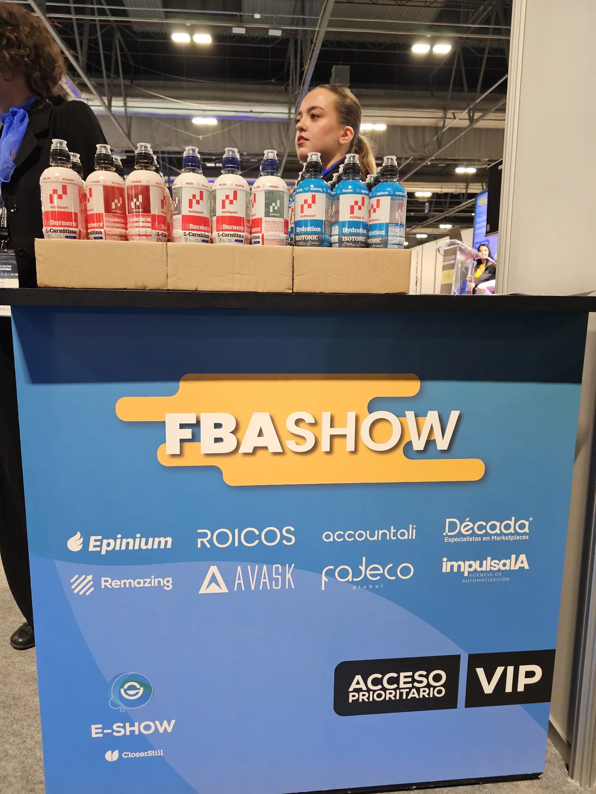 Mostrador de FBAshow Madrid 2025 con el muro de patrocinadores